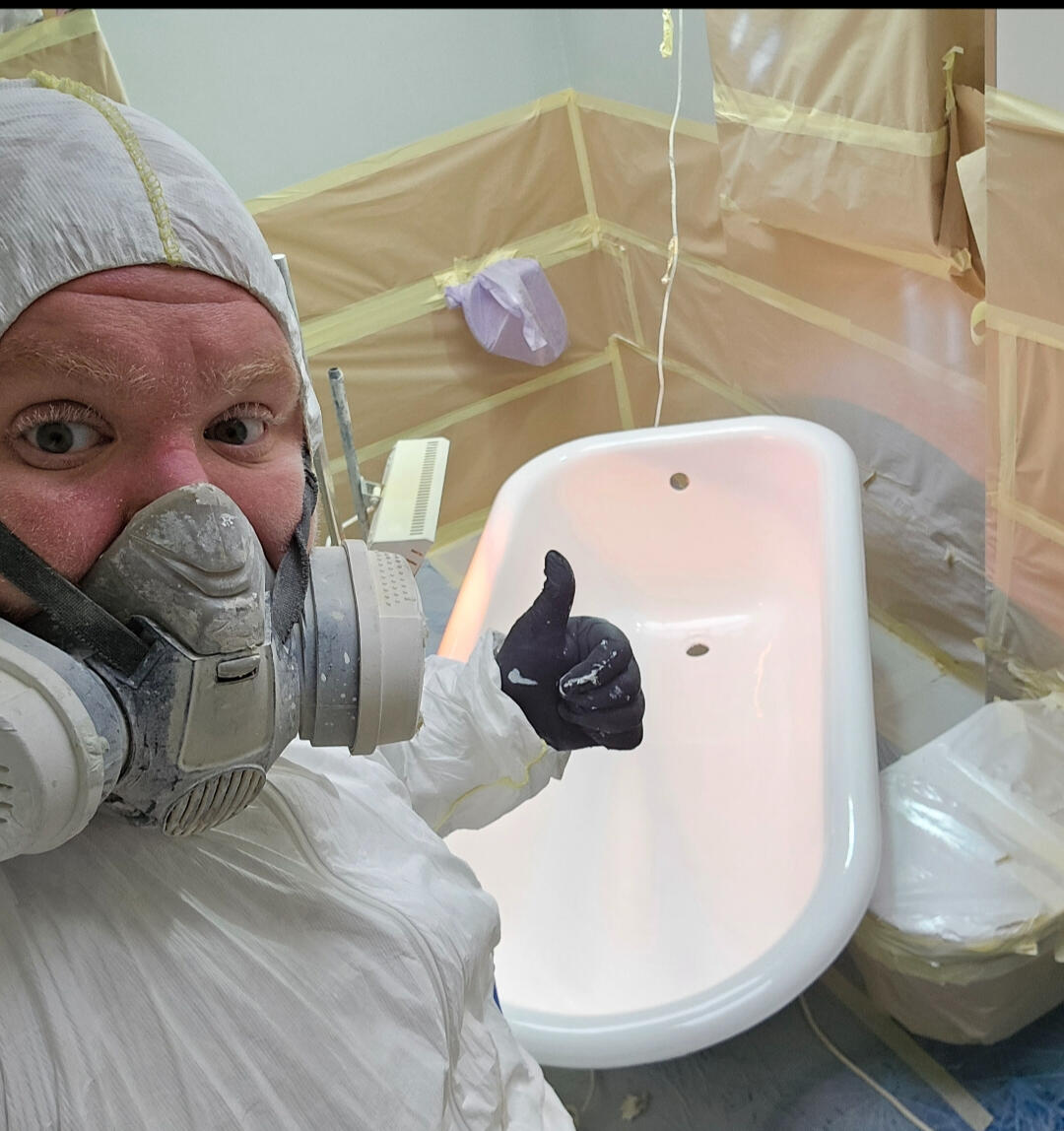photo of glossy baths owner photo of glossy baths re-enamelling owner Seamus with a thumbs up, in ppe, in a room full of masking up and a completed bath in Winchester